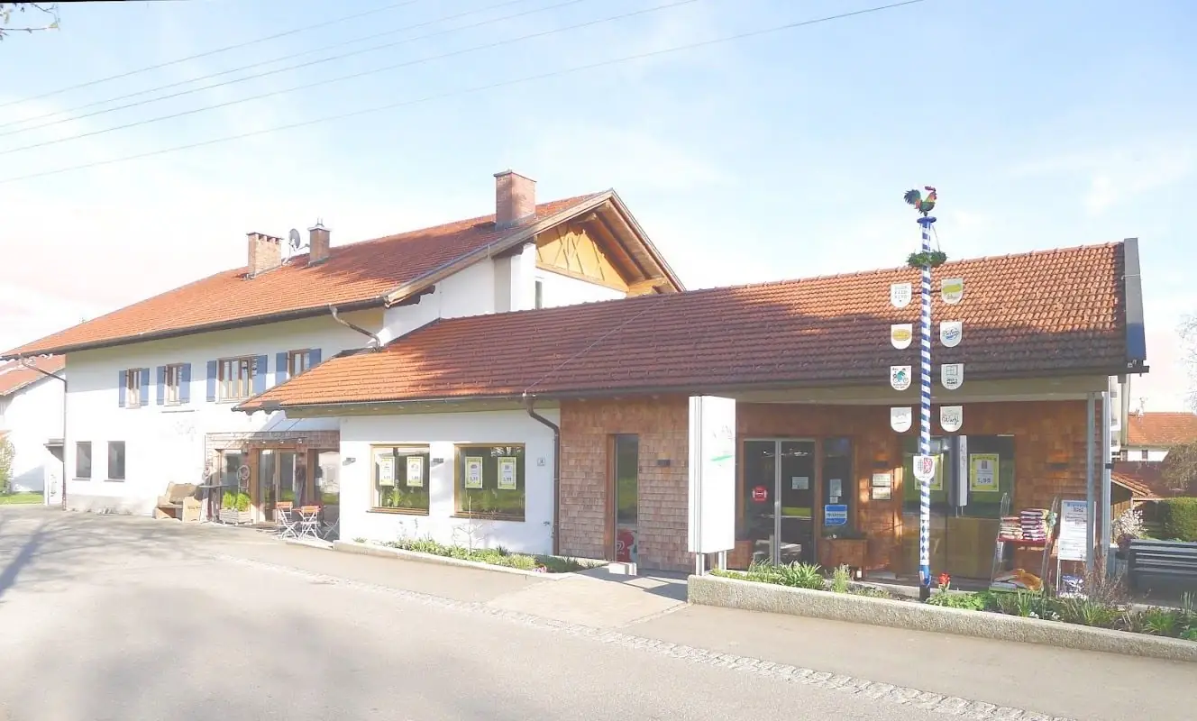 Außenansicht des Dorfladens Ingenried mit Maibaum an der Dorfstraße