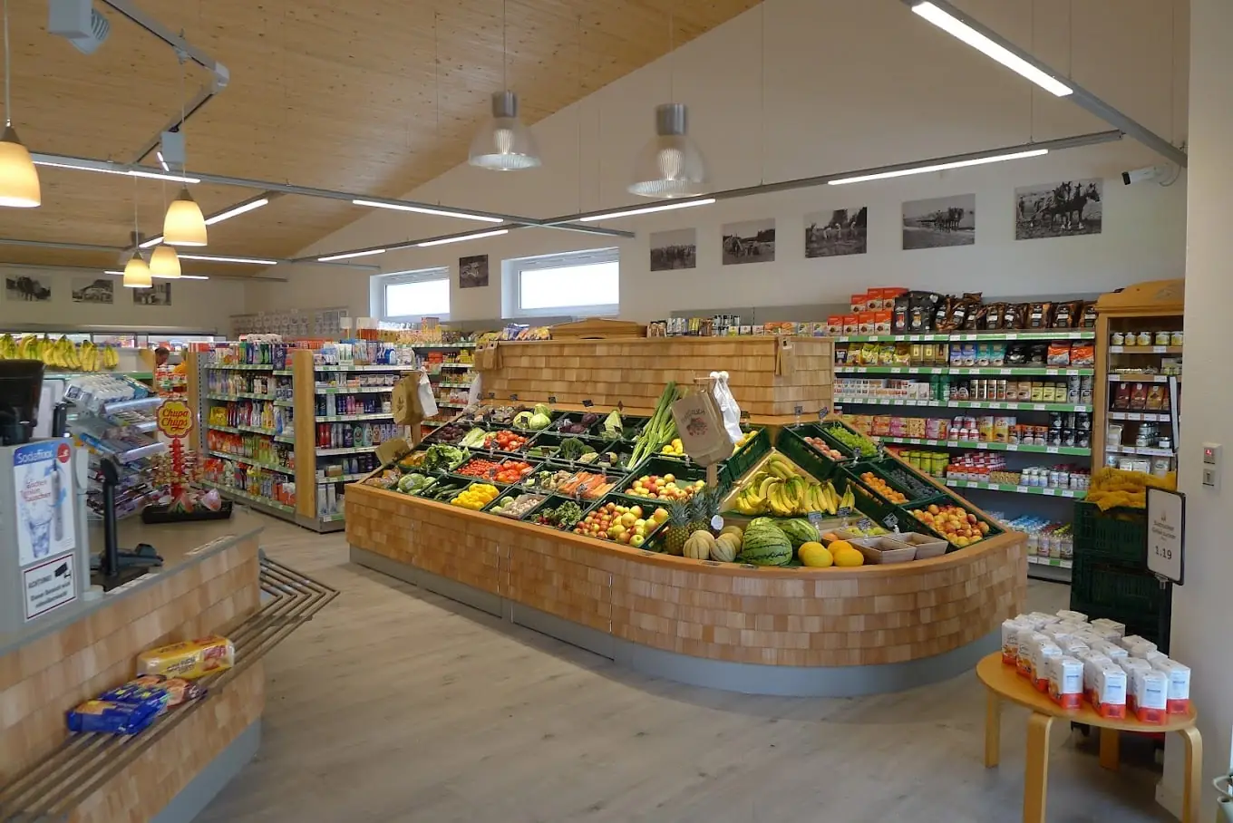 Verkaufsraum des Dorfladens Ingenried mit Lichtbändern, Pendelleuchten und Obst- und Gemüseinsel