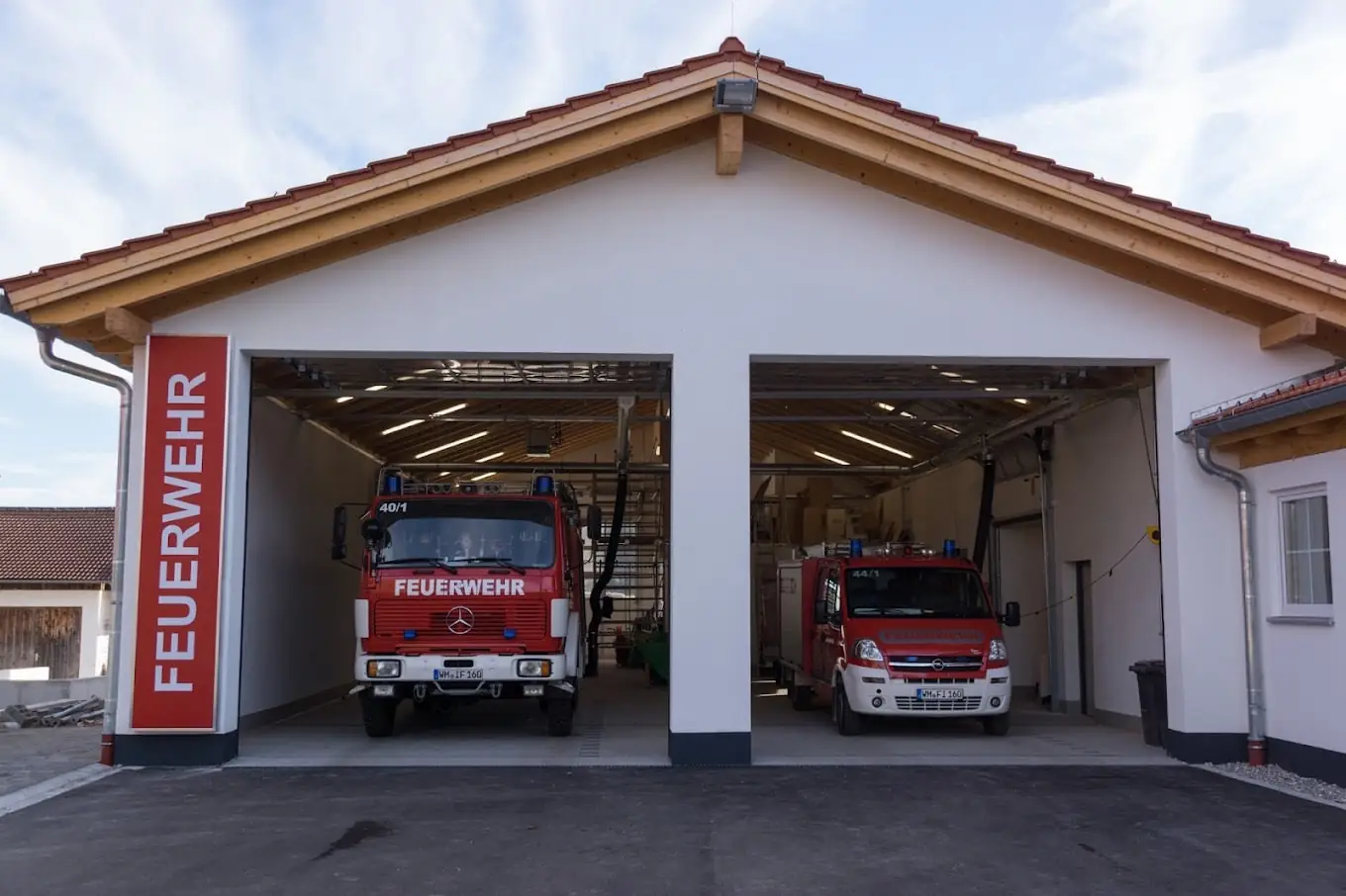 Geöffnete Tore der Fahrzeughalle des Feuerwehrhauses Ingenried mit zwei Einsatzfahrzeugen