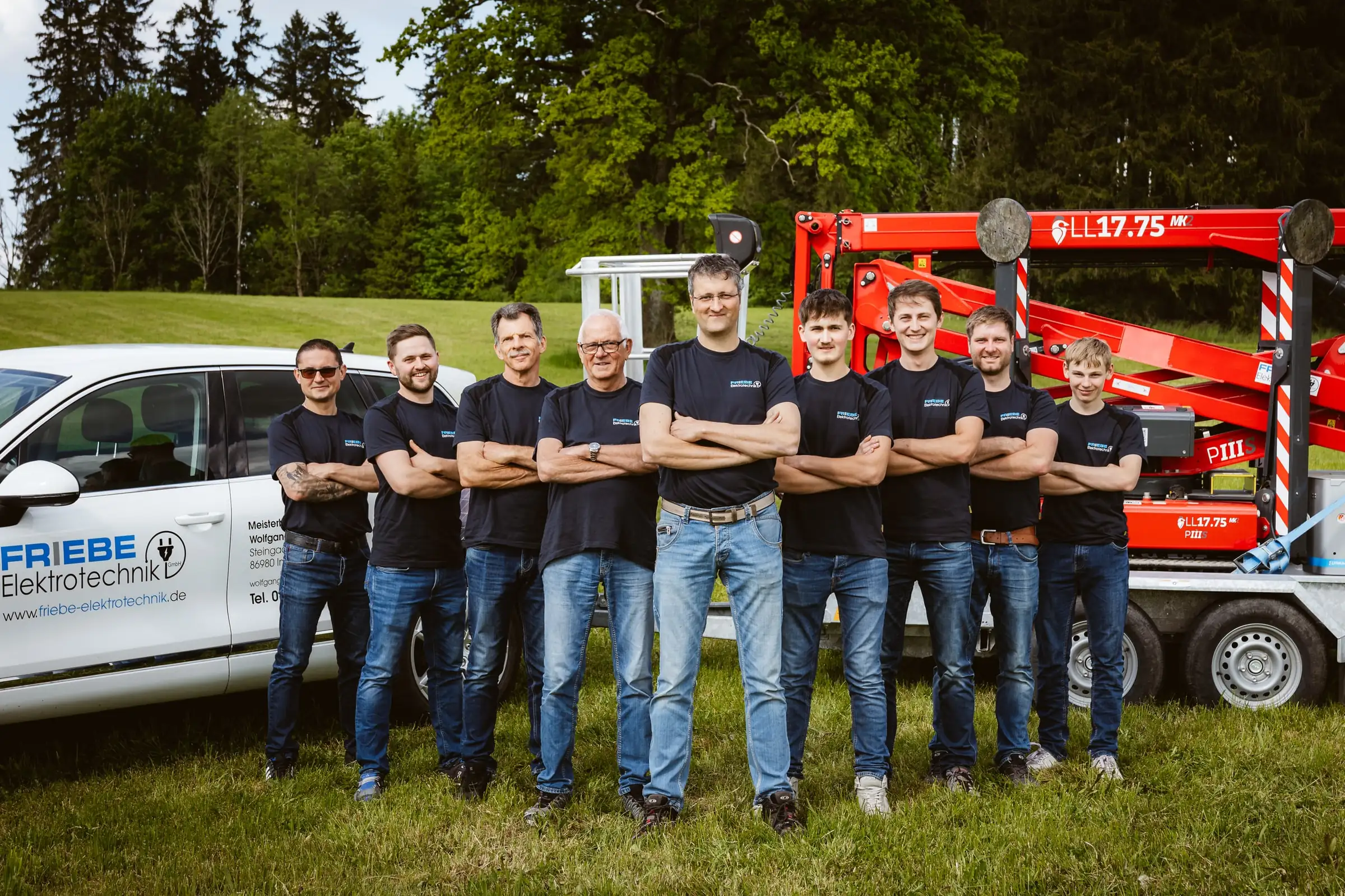 Team von Friebe Elektrotechnik mit verschränkten Armen vor Firmenwagen und Arbeitsbühne