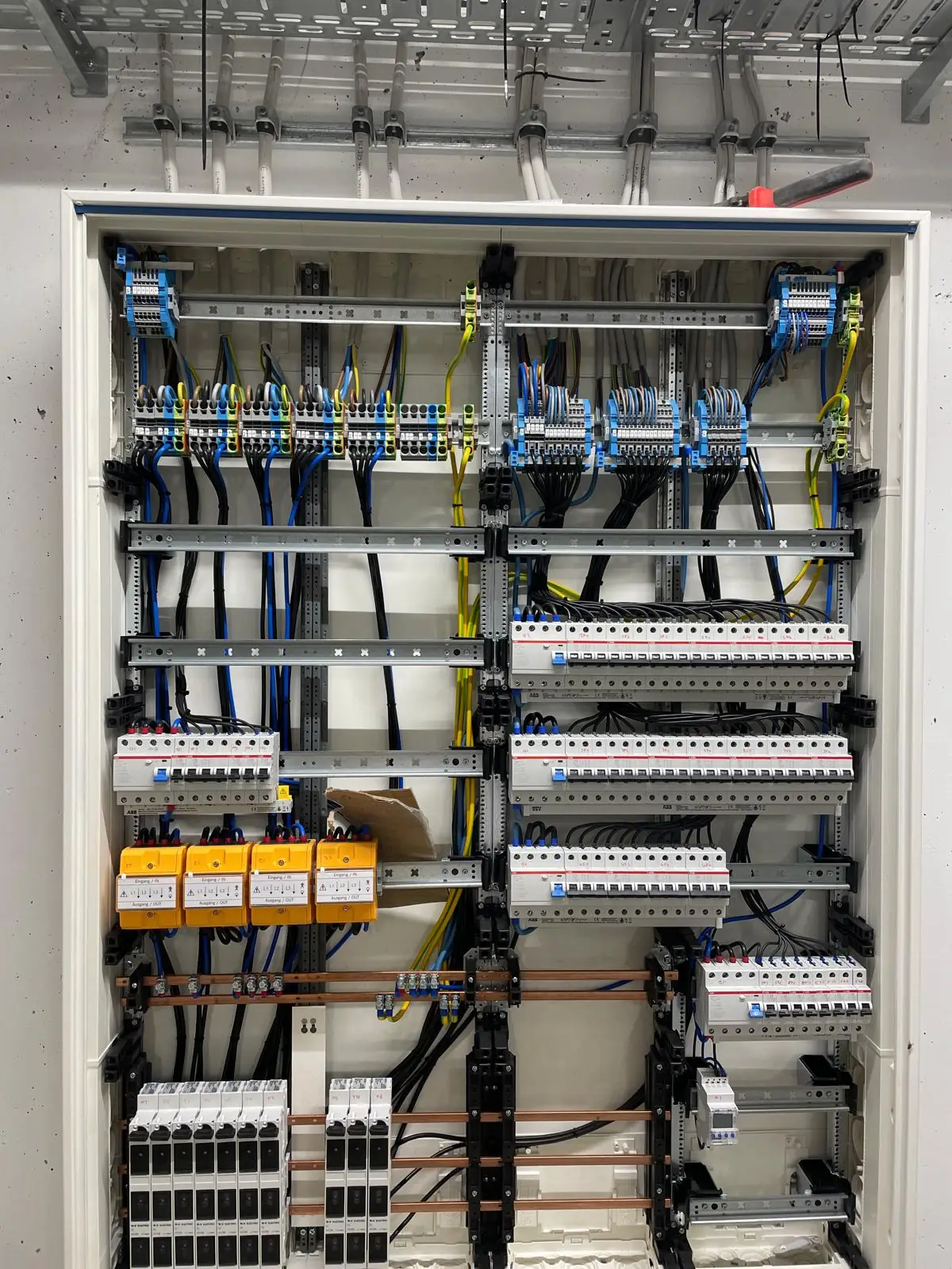 Geöffneter Elektroverteiler mit sauber verdrahteten Sicherungsautomaten und Klemmen