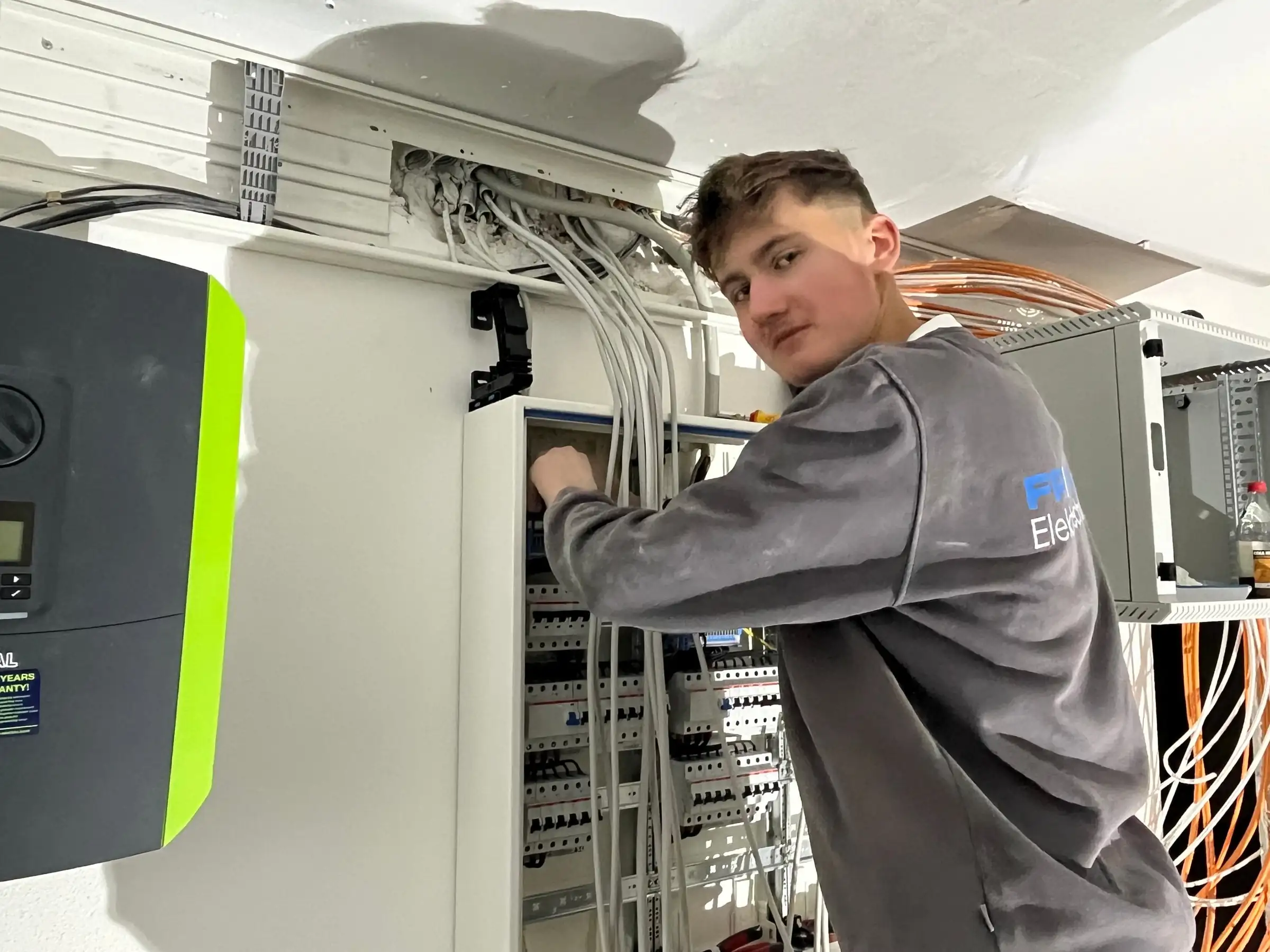 Monteur von Friebe Elektrotechnik an einer Verteilung neben einem Wechselrichter