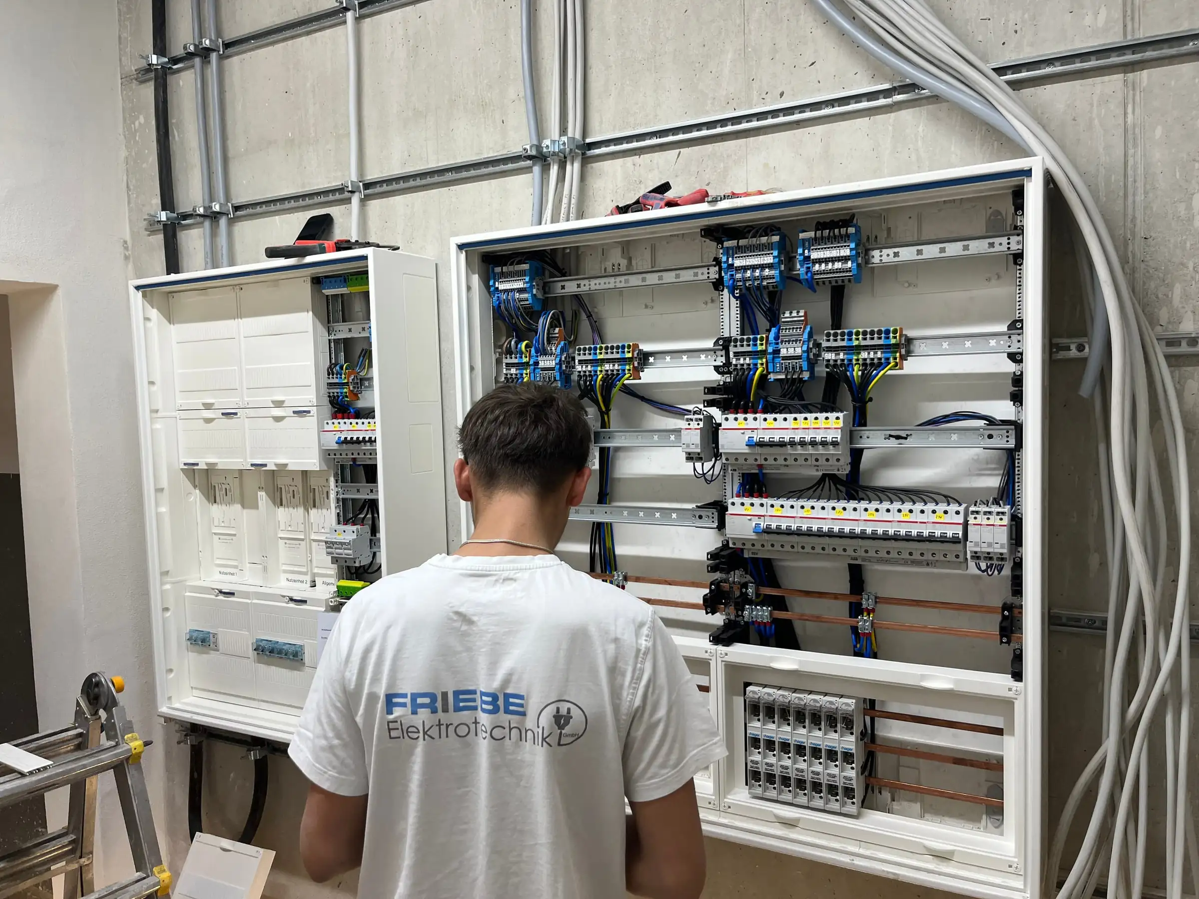 Monteur von Friebe Elektrotechnik verdrahtet eine große Unterverteilung in einem Gewerbebau